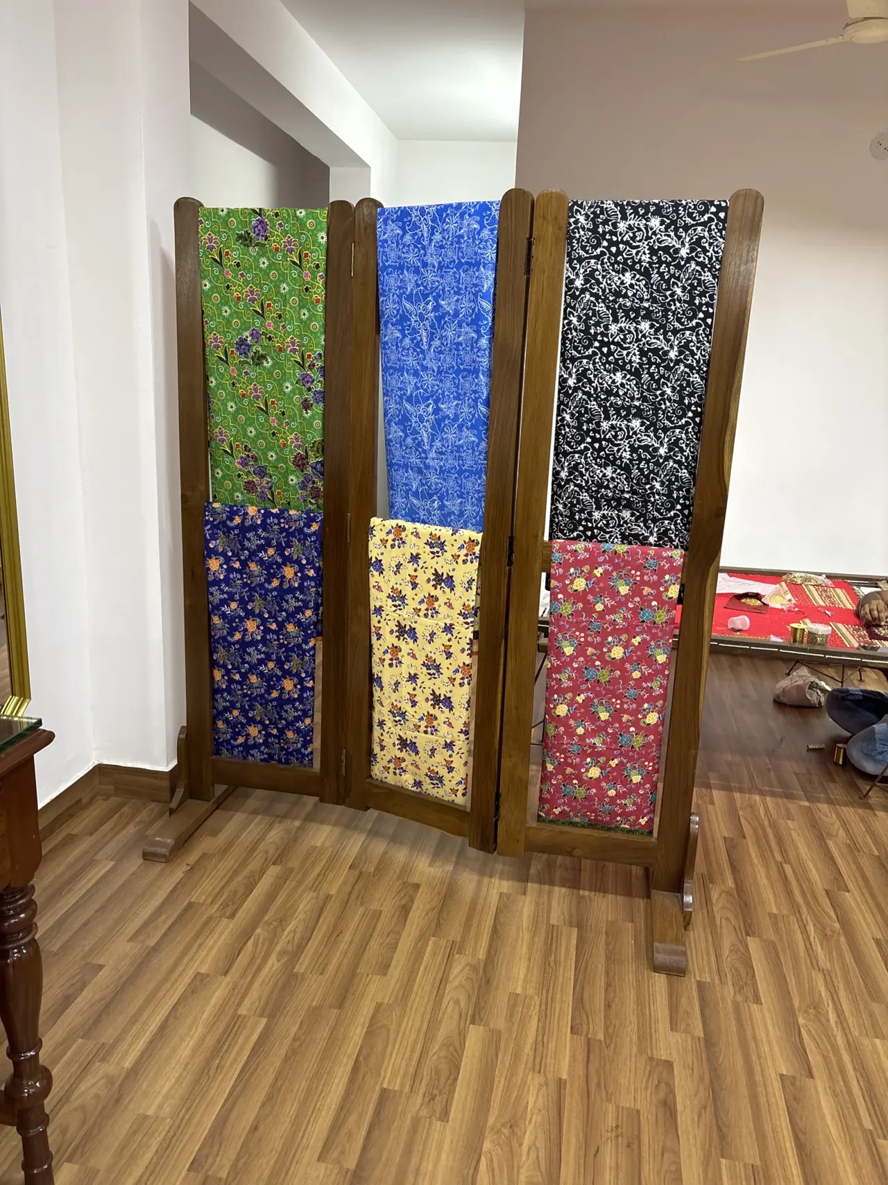 A folding screen displaying printed and embroidered fabric panels.